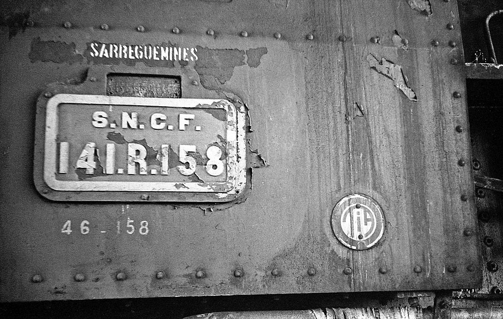 1962 hat die SNCF  für ihre Dampflokomotiven zweistellige Baureihen-Nummern eingeführt, um die Lokomotivbezeichnungen als reine Zifferngruppen für die elektronische Datenverarbeitung fit zu machen. Diese Nummern wurden zusätzlich angeschrieben. Die kohlegefeuerten 141 R 1 - 700 erhielten die Reihenbezeichnung 46, die Ordnungsnummern blieben, wie auch hier in diesem Beispiel, in den meisten Fällen erhalten. Die Leerstelle am oberen Rand des Nummernschilds nahm gewöhnlich ein Gussschild mit dem Namen des beheimatenden Bahnbetriebswerks auf. Die Plakette TIA unten rechts bezeichnet "Traitement Interne Intégral Armand", eine Anlage zur inneren Speisewasseraufbereitung, die sich auf dem Tender über dem Wasserkasten befand.